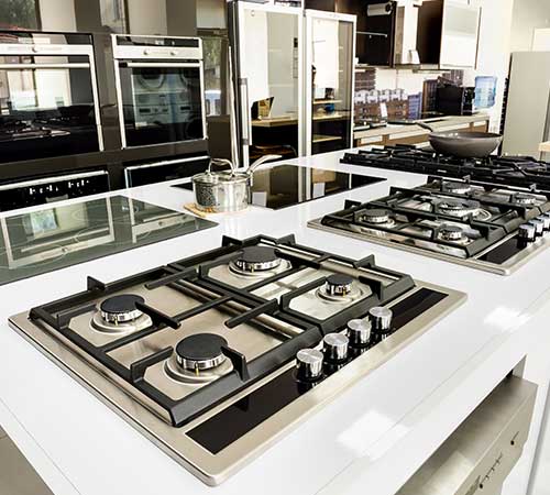 KG - Rows of brand new gas stoves and ovens with stainless steel trays in appliance at store in Pawtucket RI near Providence