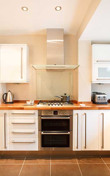 KG - Modern white kitchen with wooden worktops and stainless steel appliances